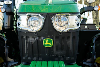 Green John Deere tractor front view with dual headlights and yellow deer logo