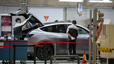 Workers check on the Tesla Model Y at the production lines at the Tesla Gigafactory assembly plant during a media organized tour, in Shanghai, China, Tuesday, April 14, 2026.
