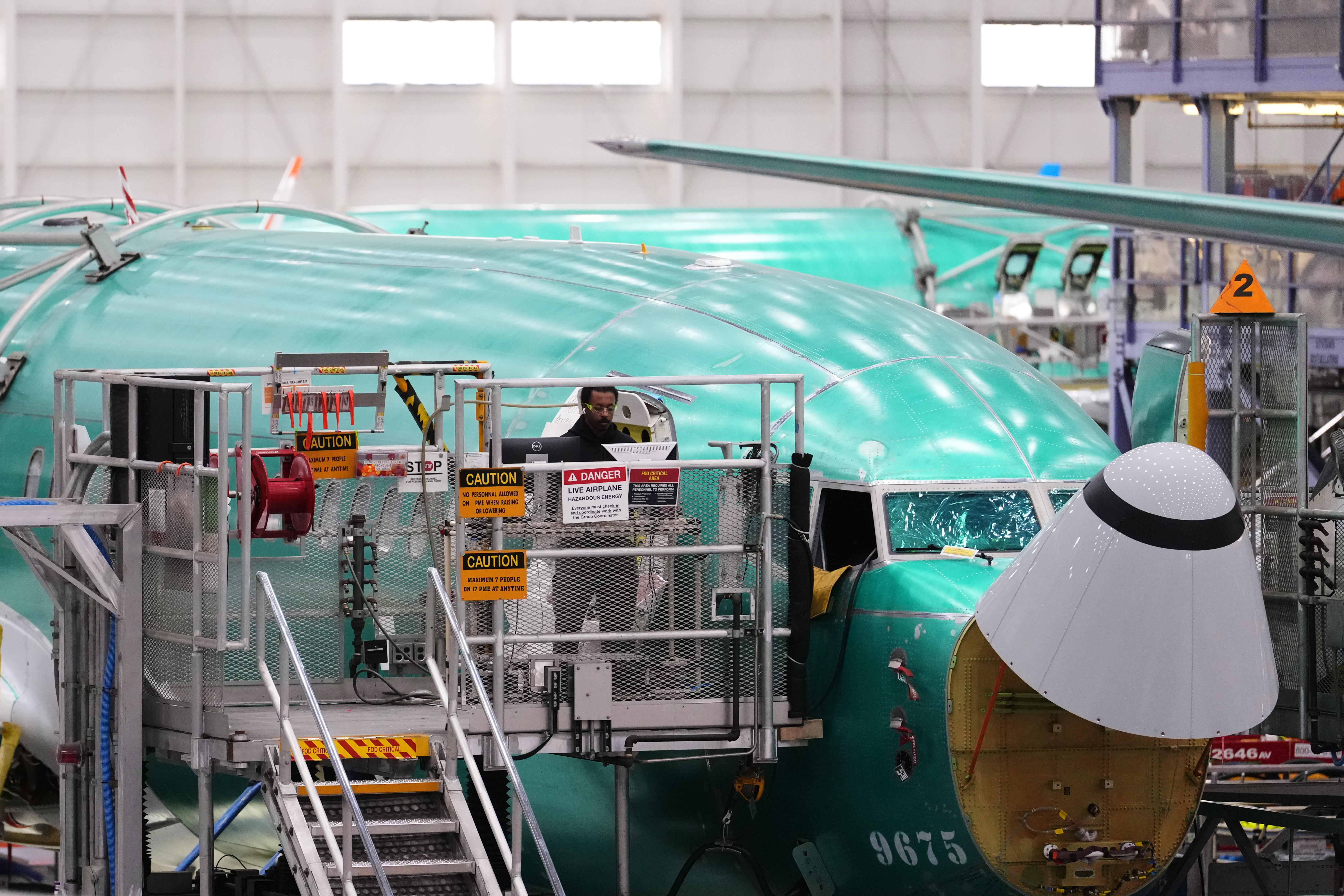 An employee works on a computer next to a Boeing 737 MAX airplane being built on the final assembly line during a media tour at Boeing's factory Wednesday, April 15, 2026, in Renton, Wash.