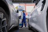 Khatawut Junsongsaeng, a charging station manager, walks past two Chinese-made electric vehicles at a parking lot in Bangkok, Thailand on June 4, 2026.