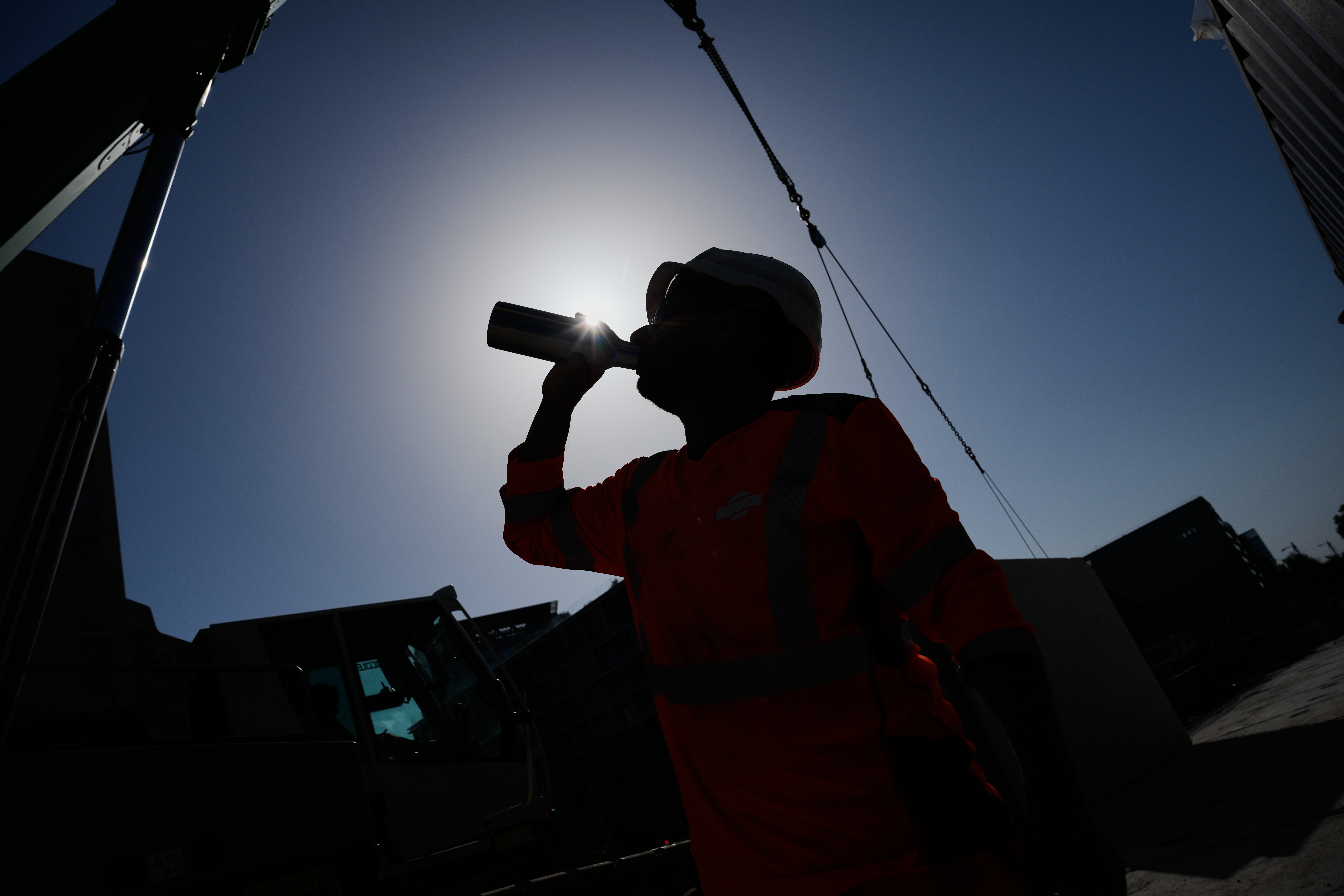 A worker drinks water on a construction site during high temperatures in Boulogne Billancourt, outside Paris, Wednesday, June 24, 2026.