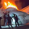 A passenger, top, jumps out of a plane after it crashed on a highway as other people help Tuesday, June 16, 2026, in Laredo, Texas.