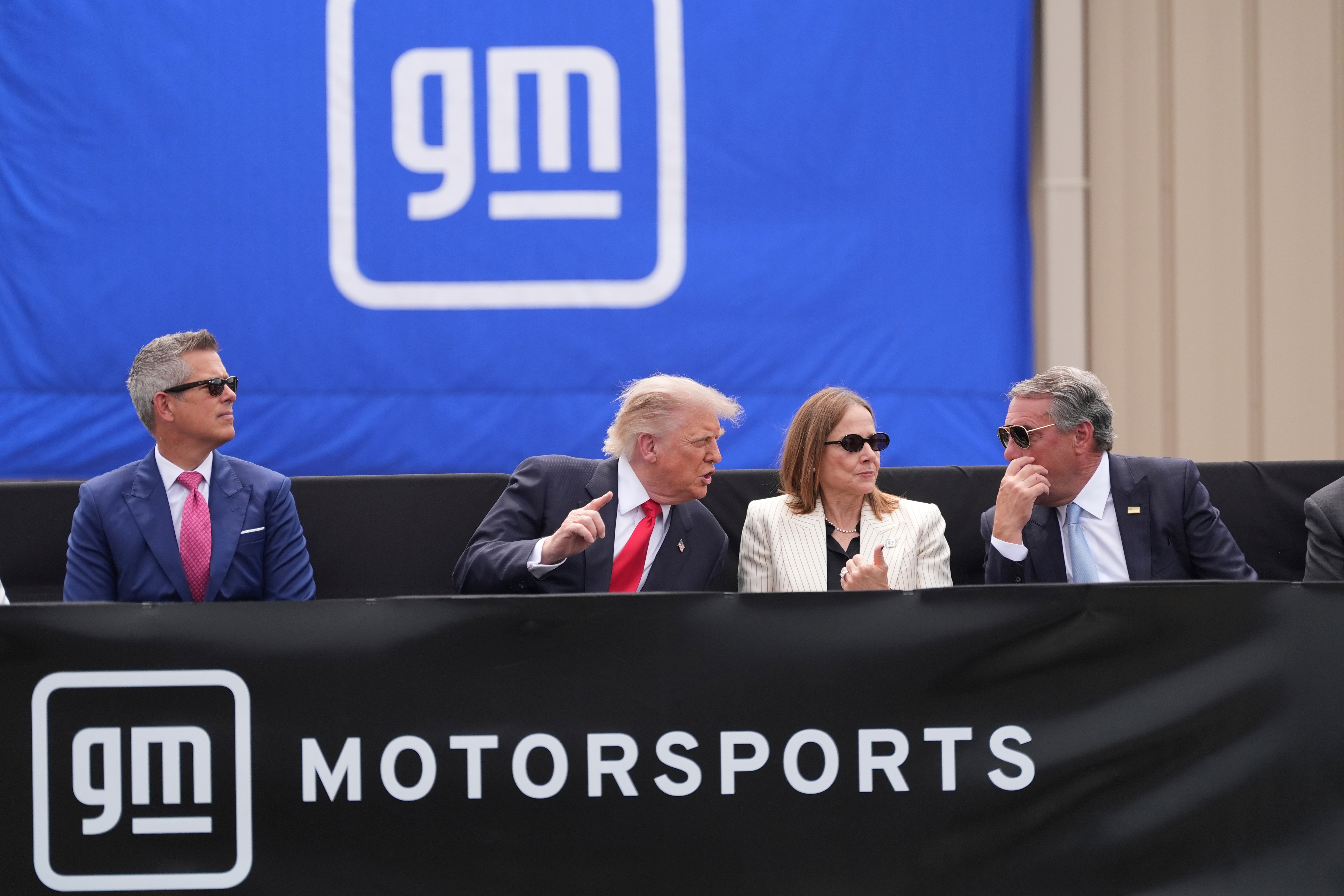 President Donald Trump, center left, speaks with Mary Barra, chair and CEO of General Motors, center right, and General Motors President Mark Reuss, right, as Transportation Secretary Sean Duffy listens at left, during a driving demonstration at General Motors proving ground, Monday, July 27, 2026, in Milford, Mich.