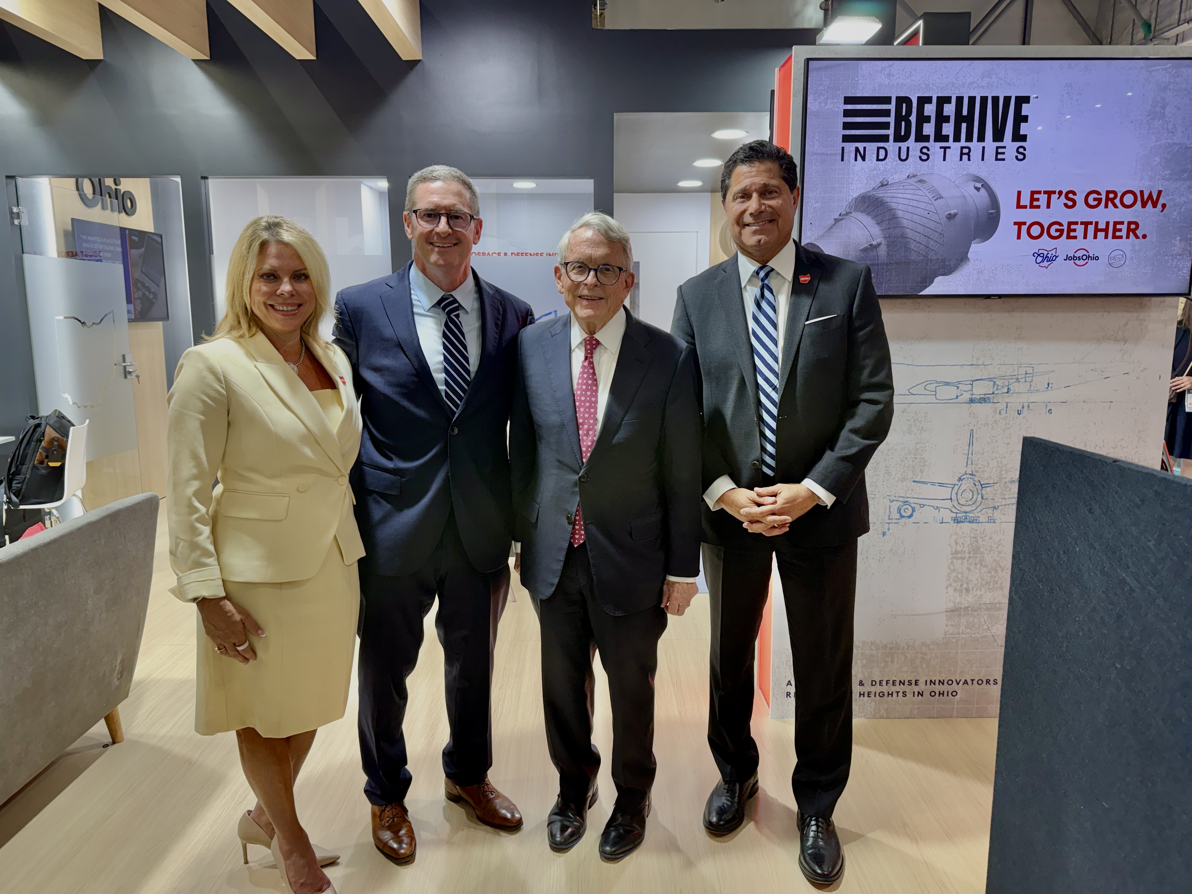 Leaders gather at the Farnborough International Airshow to announce Beehive Industries' $70 million expansion in Southwest Ohio. From left to right: Kimm Lauterbach, President and CEO of REDI Cincinnati; Gordie Follin, Chief Product Officer at Beehive Industries; Mike DeWine, Governor of Ohio; and J.P. Nauseef, President and CEO of JobsOhio.
