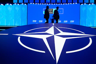 Two men walk past the NATO logo during the NATO Defense Industry Forum at the NATO summit in Ankara, Turkey, Tuesday, July 7, 2026.