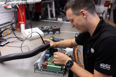 Technician working on circuit board assembly with soldering equipment in electronics repair workshop
