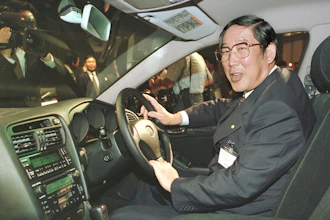 Hiroshi Okuda, then, president of Toyota Motor Corp., smiles as he sits at the steering wheel of the 'Aristo,' Toyota's remodeled sports sedan during a press conference at a Tokyo hotel, Aug. 27, 1997.