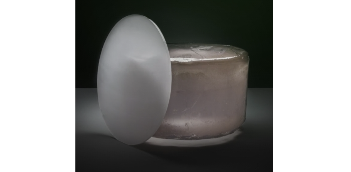 White egg-shaped object beside a translucent jar on dark background