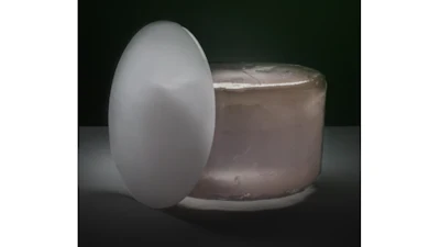 White egg-shaped object beside a translucent jar on dark background