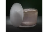 White egg-shaped object beside a translucent jar on dark background