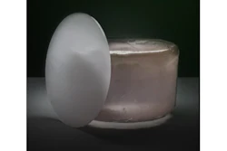 White egg-shaped object beside a translucent jar on dark background