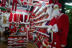 A vendor waits for customers near Santa costumes for sale at the Yiwu International Trade Market in Yiwu, eastern China's Zhejiang province on April 10, 2025.