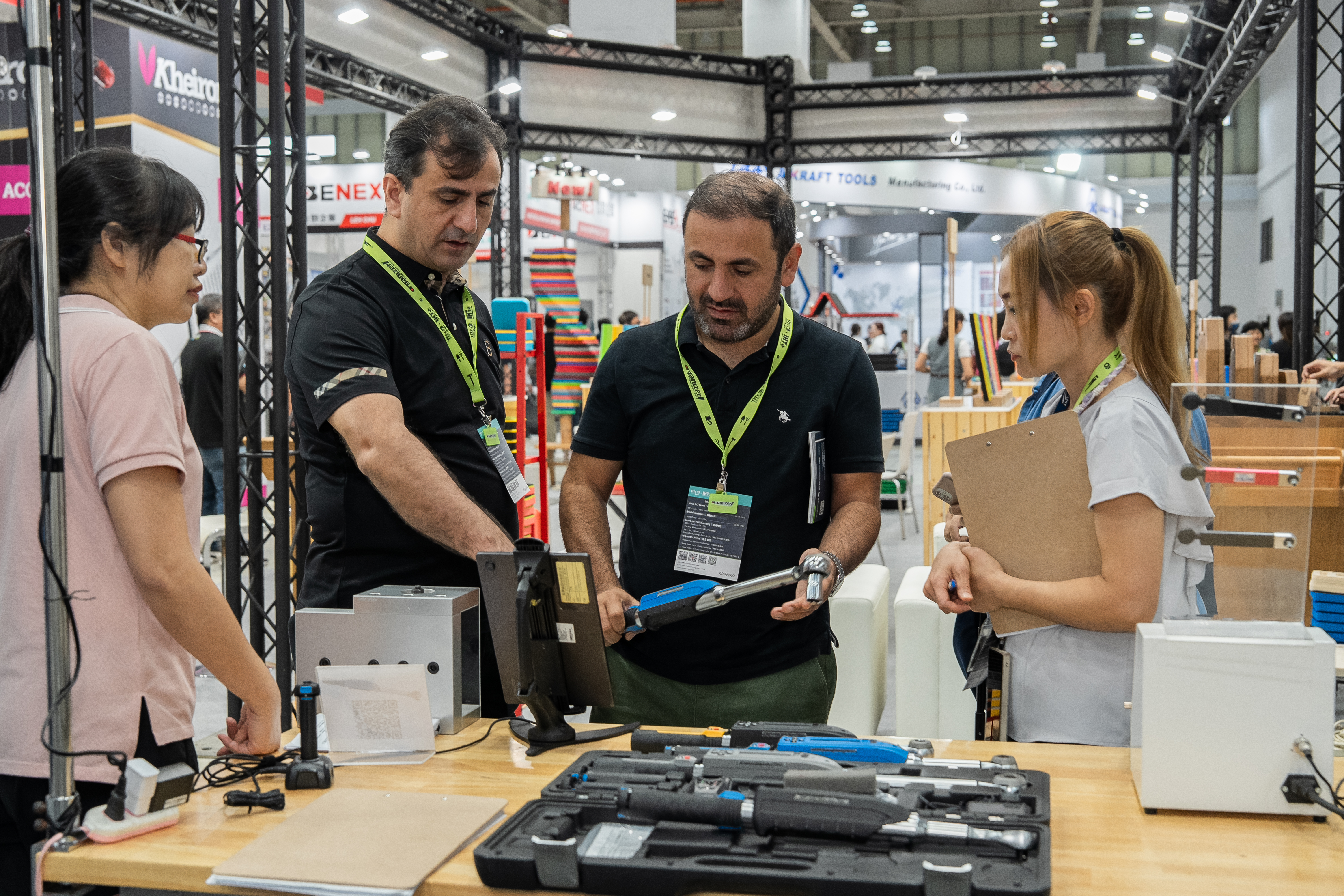 Trade show booth demonstration with staff and visitors examining tools and equipment at an industrial exhibition