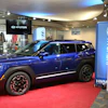 Blue Hyundai Kona electric vehicle displayed in modern showroom with branded signage and red carpet