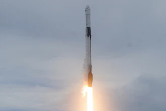 Rocket launching vertically with bright orange flame exhaust against cloudy sky