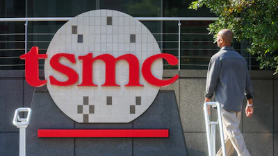 TSMC logo displayed on building exterior signage with person walking past