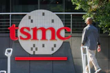 TSMC logo displayed on building exterior signage with person walking past