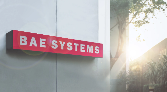 BAE Systems red and white exterior building sign mounted on modern facade with natural sunlight