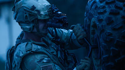 Tactical operator in full combat gear with rifle and night vision equipment in blue-toned lighting