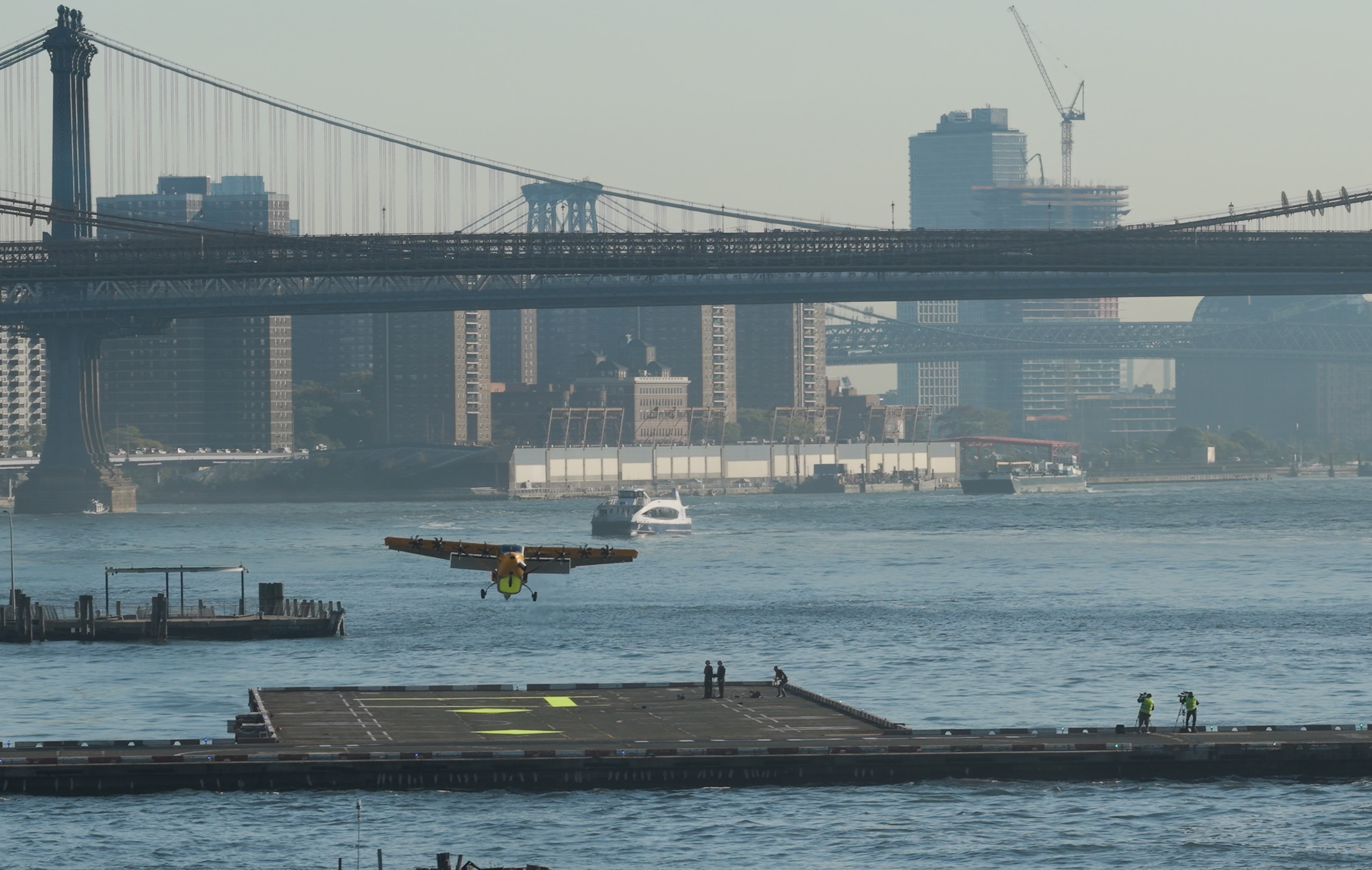 Seaplane landing on East River near Manhattan Bridge with NYC skyline in background