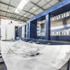 Industrial CNC sheet metal processing machine with blue frame in modern manufacturing facility