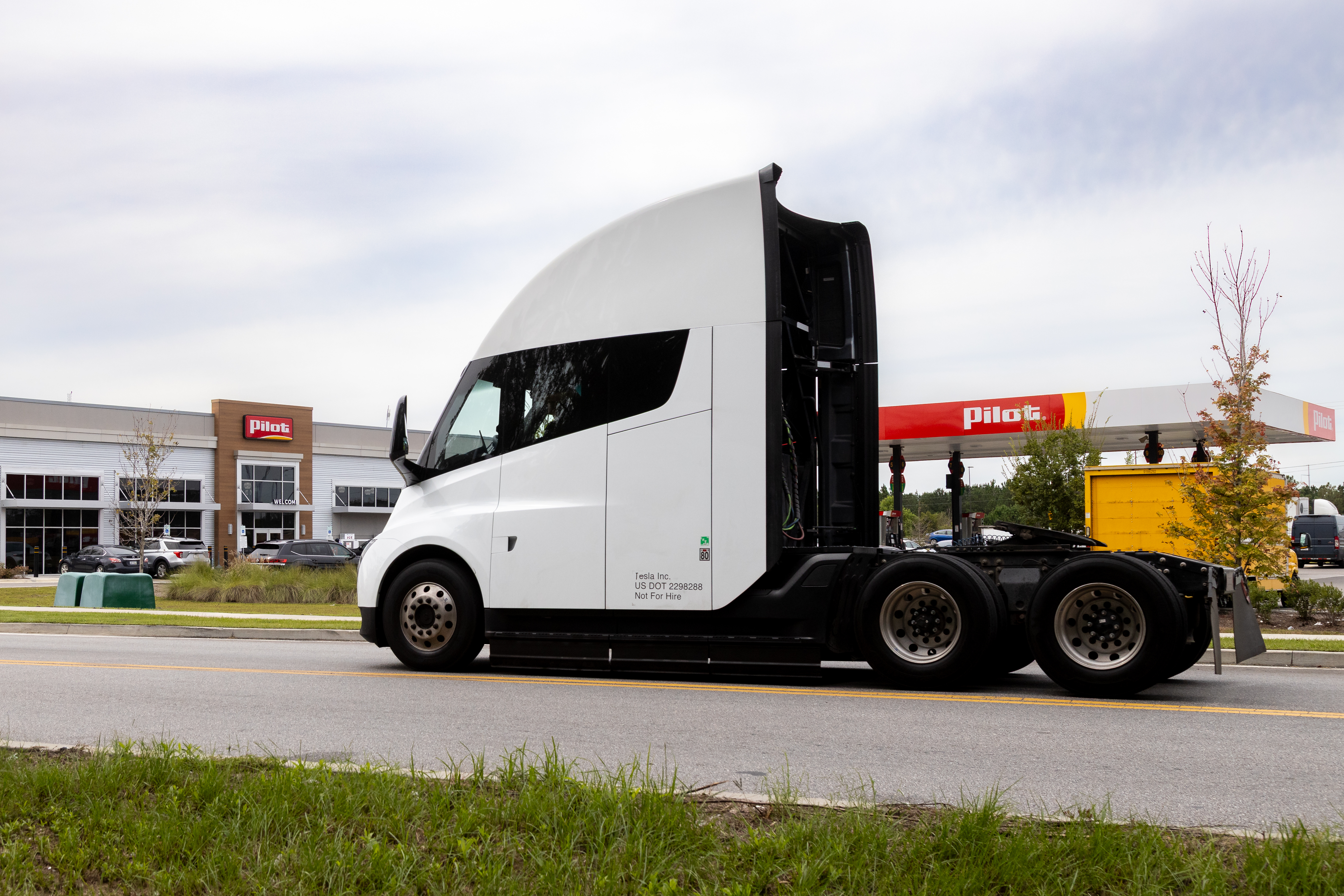 White semi-truck parked at Plas fuel station with open sleeper cab door