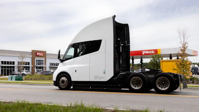 White semi-truck parked at Plas fuel station with open sleeper cab door