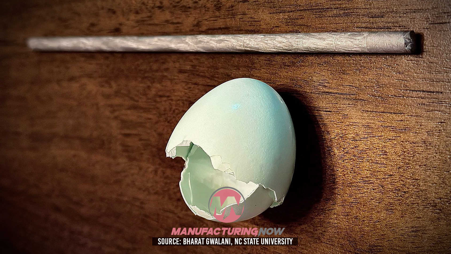 Broken eggshell on wooden surface revealing manufacturing-related graphic inside
