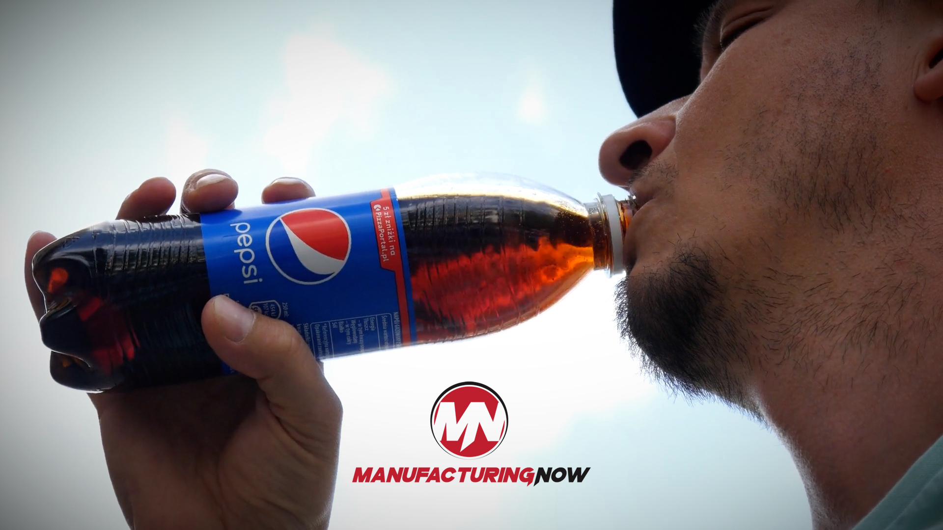 Man drinking from a Pepsi bottle against a cloudy sky with Manufacturing Now branding