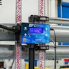 EFC blue control device mounted on industrial factory equipment with colorful overhead cables and structural beams