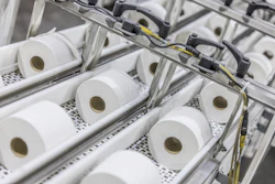 Industrial production line with multiple white tissue paper rolls on conveyor system with mechanical components and yellow wiring