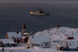 Arctic coastal settlement with red church, snow-covered buildings, and icebreaker ship in Greenlandic waters