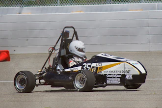 Black and white formula SAE race car with number 35 on concrete track near barrier