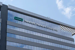 Modern glass and steel office building with company signage on facade under blue sky