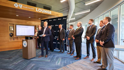 Business professionals gathered in South Carolina Lounge for corporate presentation at podium with display screen