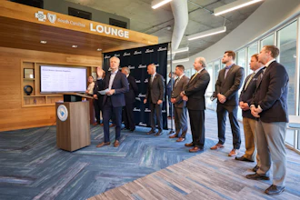 Business professionals gathered in South Carolina Lounge for corporate presentation at podium with display screen