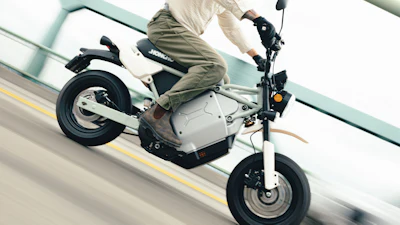 Person riding white and black electric scooter on road with yellow lane marking