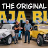 Two men stand between a white and yellow modified Baja Bug vehicles in a garage workshop setting.