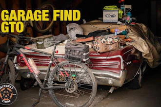 Garage find collection featuring red bicycle, car door panel, tools, and Arai helmet box on workbench