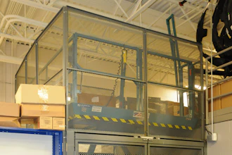 Industrial safety cage with mesh panels and yellow-black striping in warehouse facility