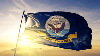 United States Navy flag waving against golden sunset sky with mountains in background