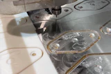 CNC machining workstation with white plastic components and metal parts with protective film during manufacturing process