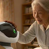 Elderly woman holding white and black robotic device with green indicator light in home setting