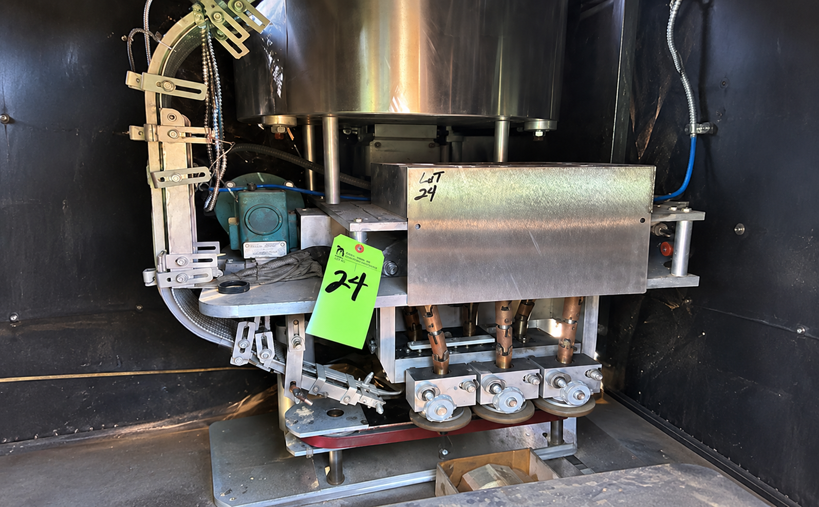 Industrial machinery with motor and metal components inside black cabinet with green asset tag