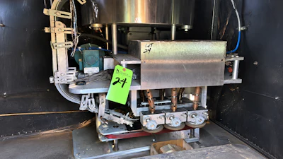 Industrial machinery with motor and metal components inside black cabinet with green asset tag