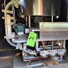 Industrial machinery with motor and metal components inside black cabinet with green asset tag
