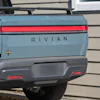 Rear view of light blue Rivian R1T electric truck with red horizontal tail lights and gray bumper