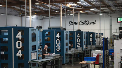 Industrial manufacturing facility with blue CNC machines and Sena CutSend signage on warehouse wall
