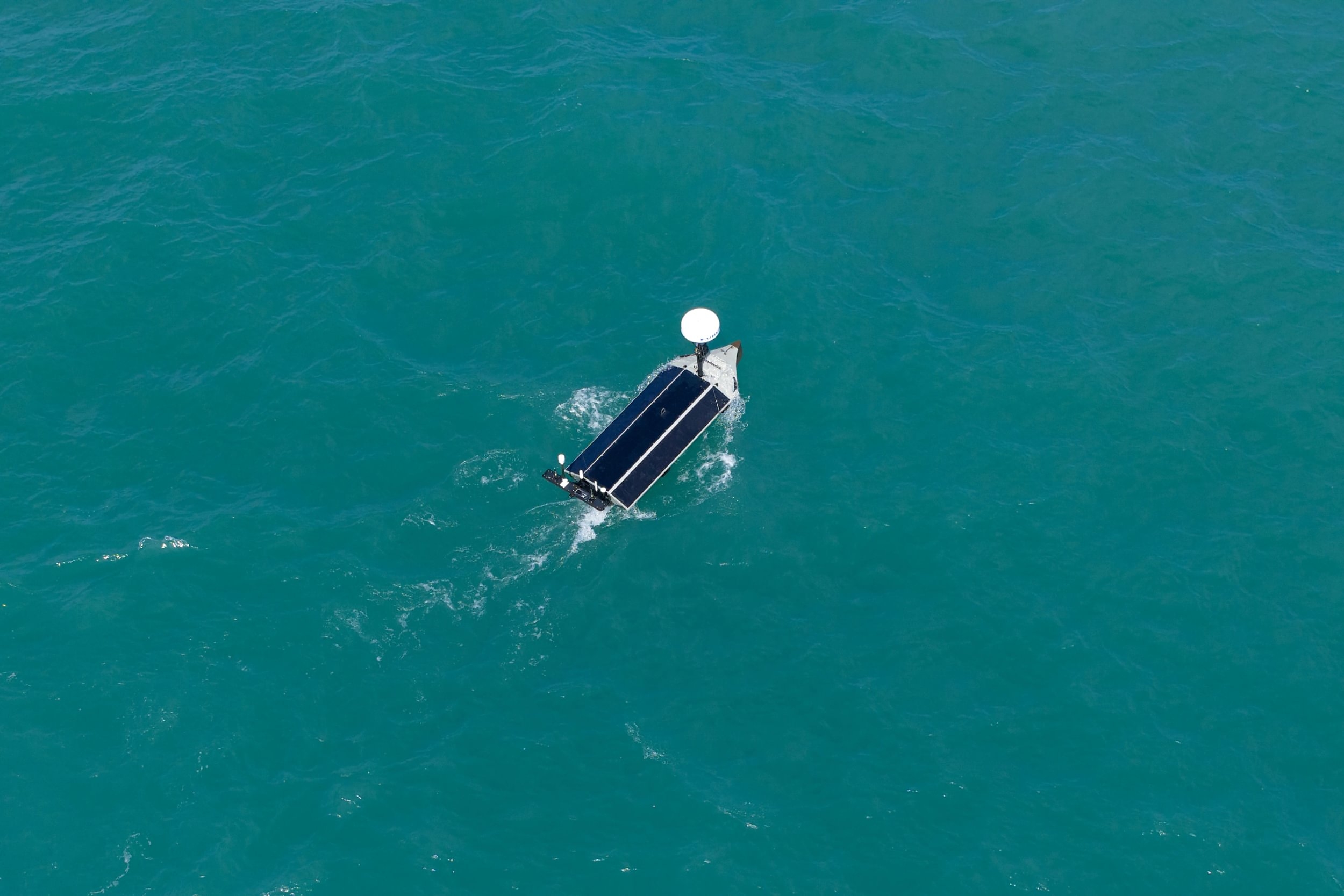 Aerial view of a pontoon boat on clear turquoise water with white canopy