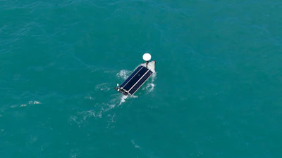 Aerial view of a pontoon boat on clear turquoise water with white canopy